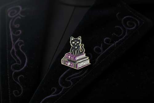 Black cat on book enamel pin worn on jacket lapel, goth pin styles for everyday wear