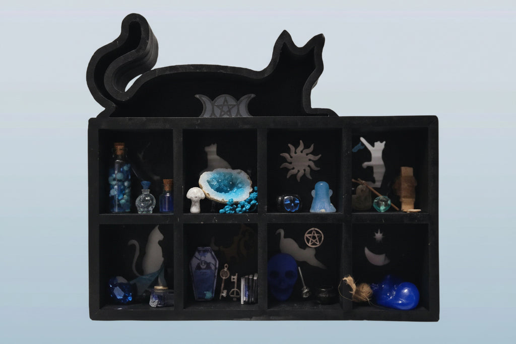 Black cat-shaped jewelry box with compartments containing various small figurines on a light blue background