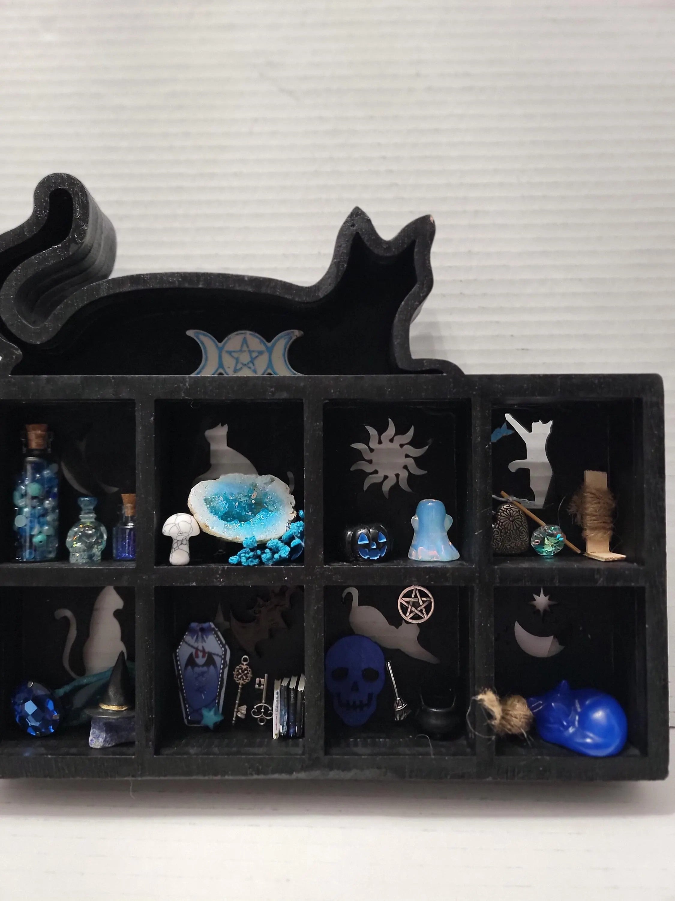 Black decorative shelf with various small objects and symbols on a white background