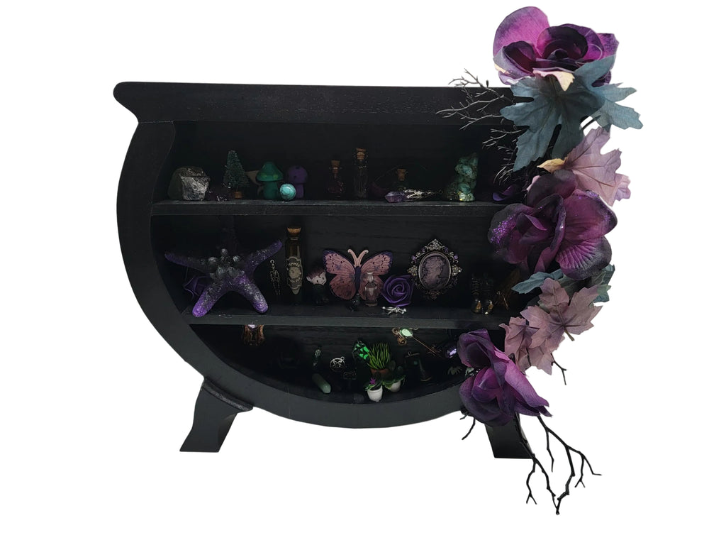 Cauldron shaped shelf filled with witchy miniatures on a white background.
