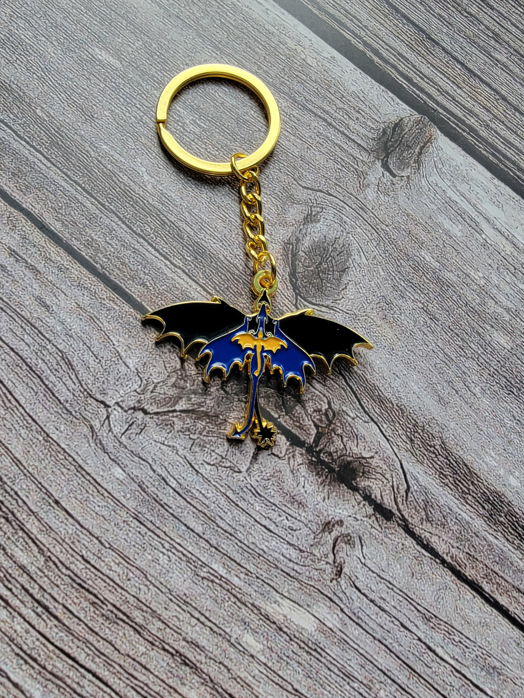 dragon-shaped keychain with gold chain on a wooden surface