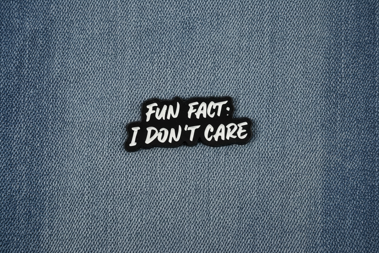Black and white enamel pin with text on a denim background