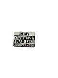 a square metal pin that is white and black with text