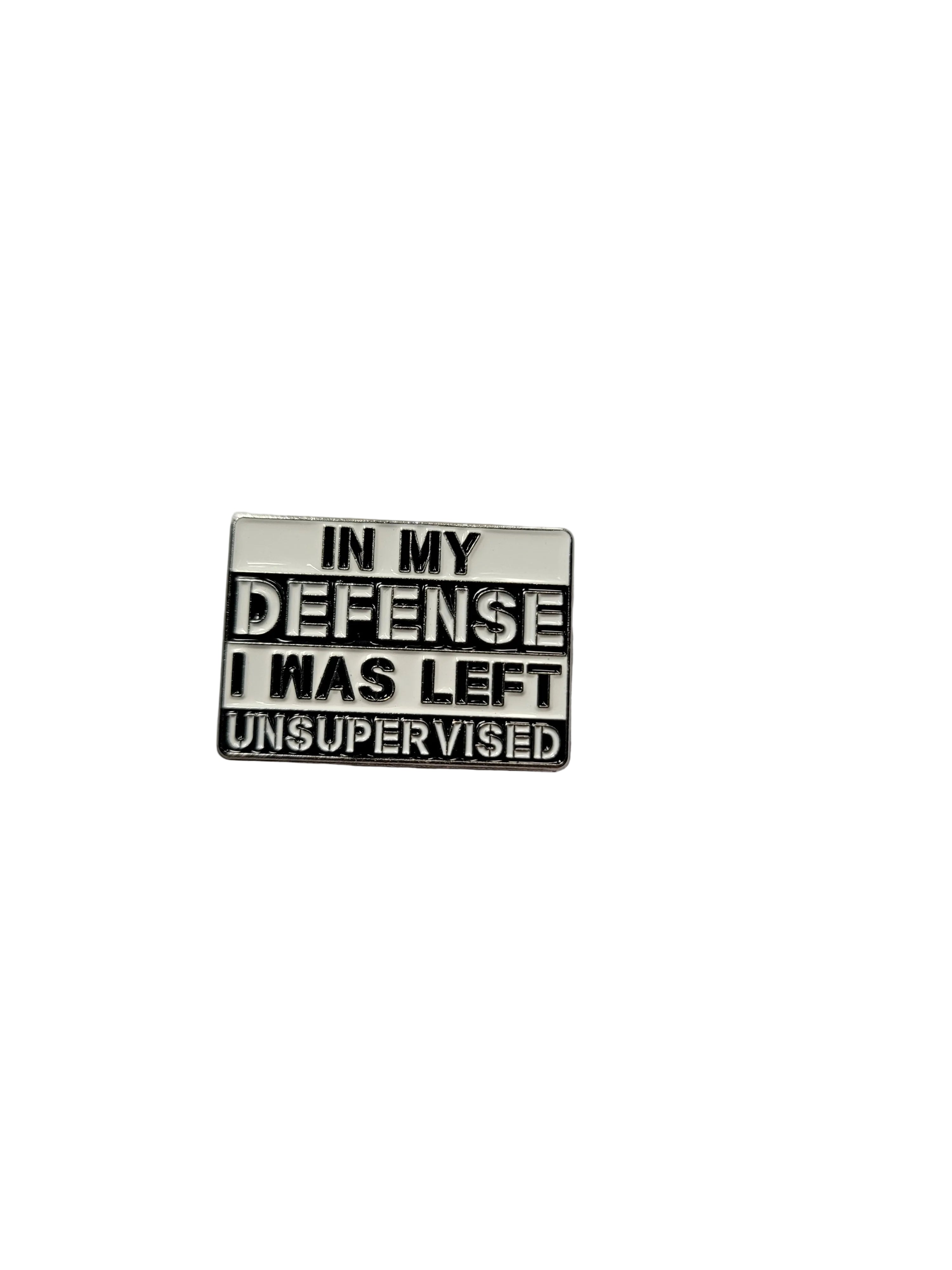 a square metal pin that is white and black with text