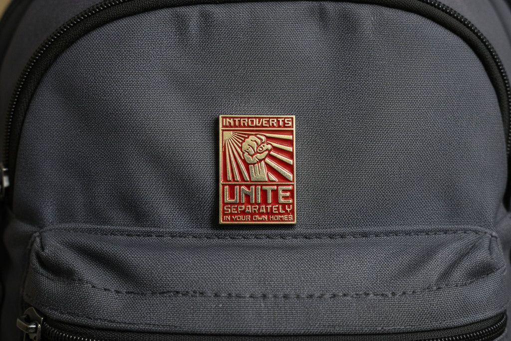 Metallic pin with text on a light gray backpack