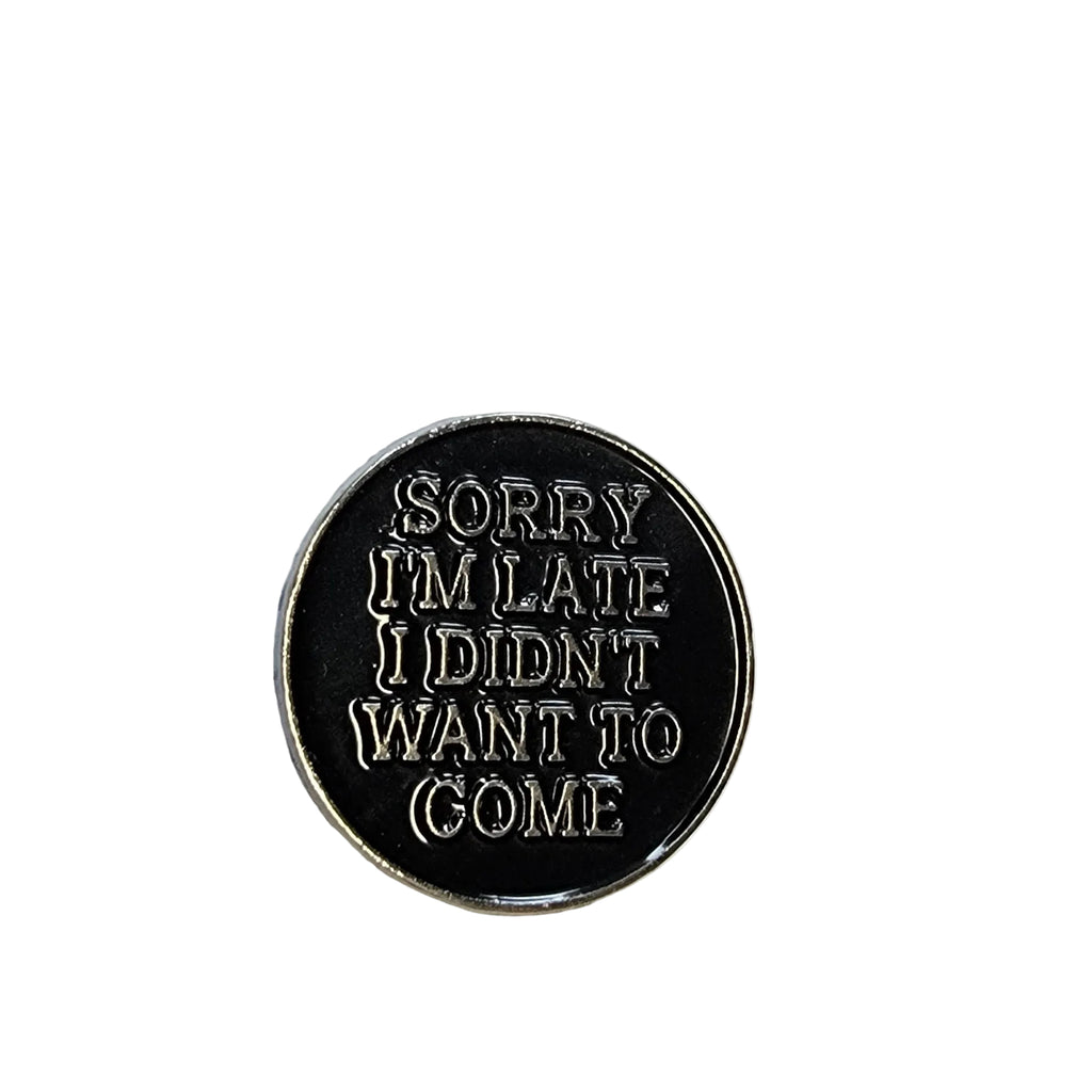 Round black metal badge with silver text on a white background