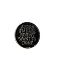 Round black metal badge with silver text on a white background