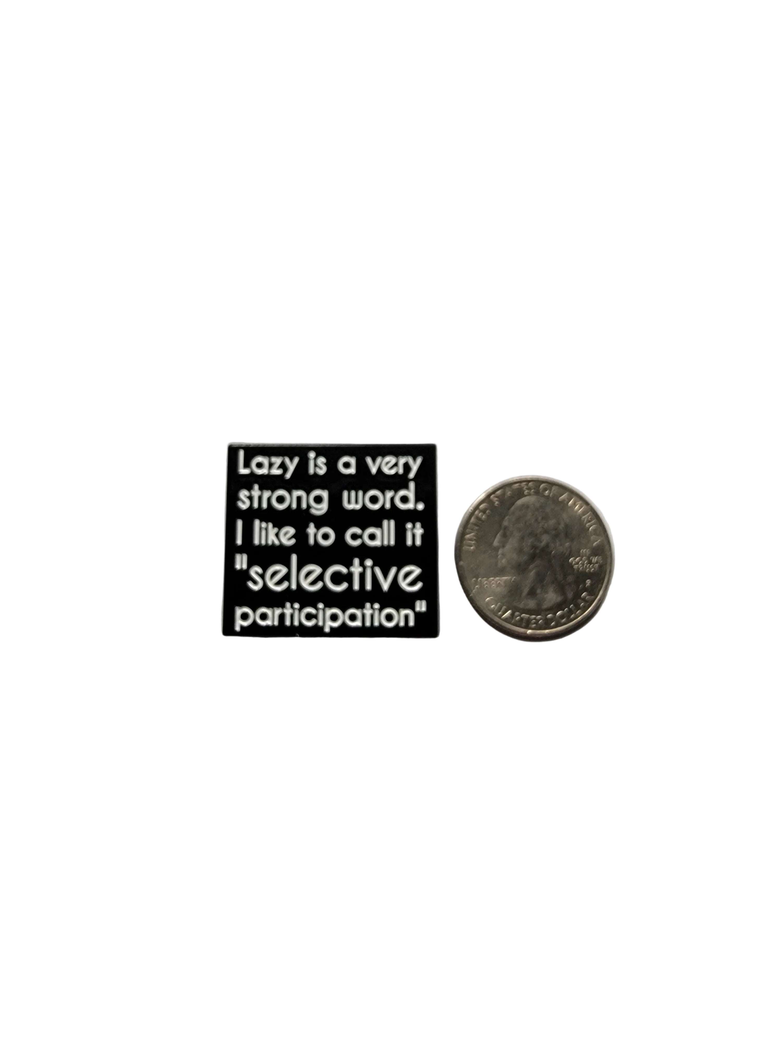 Small black square pin with text on a gray surface next to a coin.