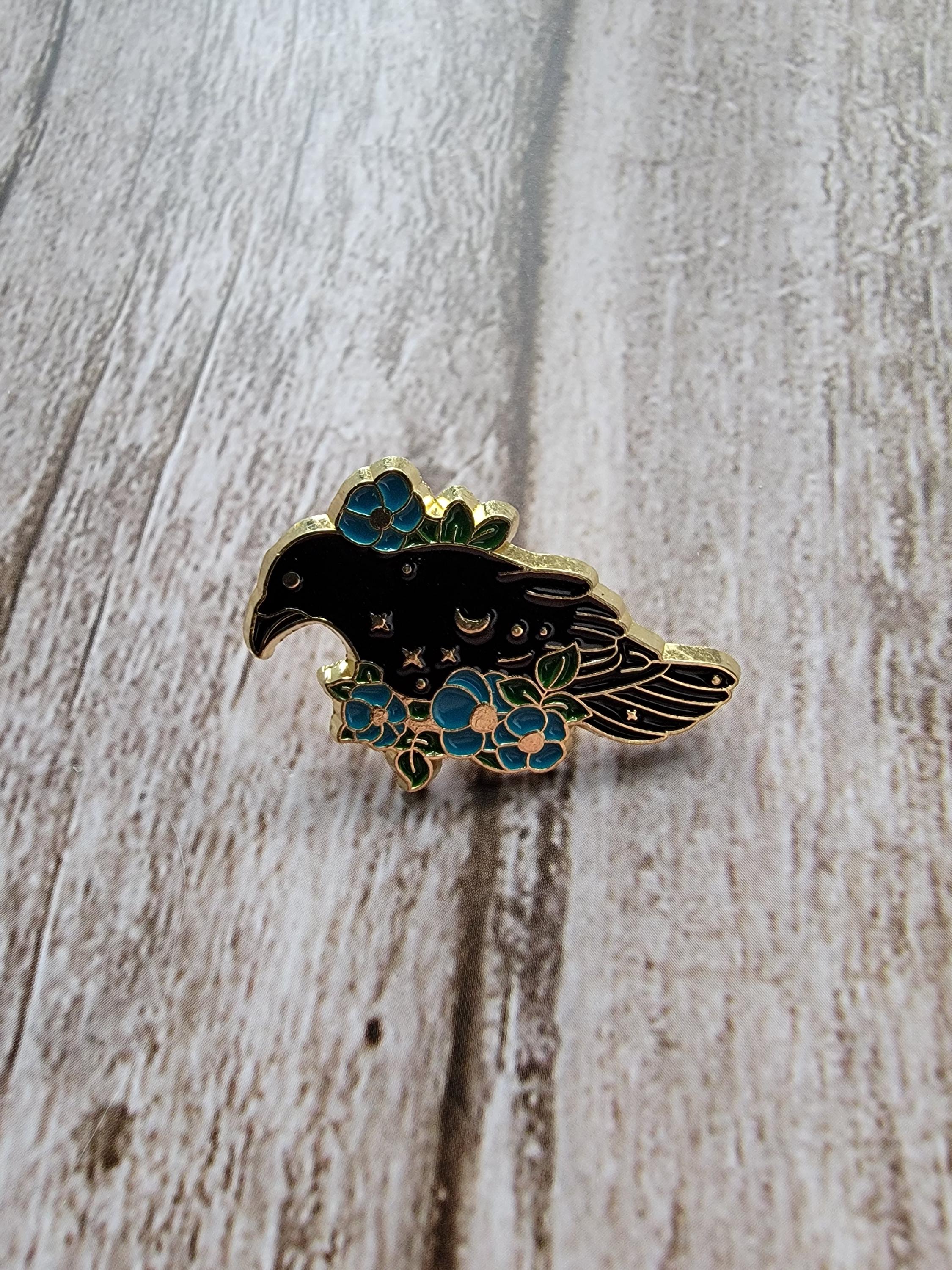 Mystical Crow Enamel Pin on wood background goth enamel pin with raven and blue flowers detail