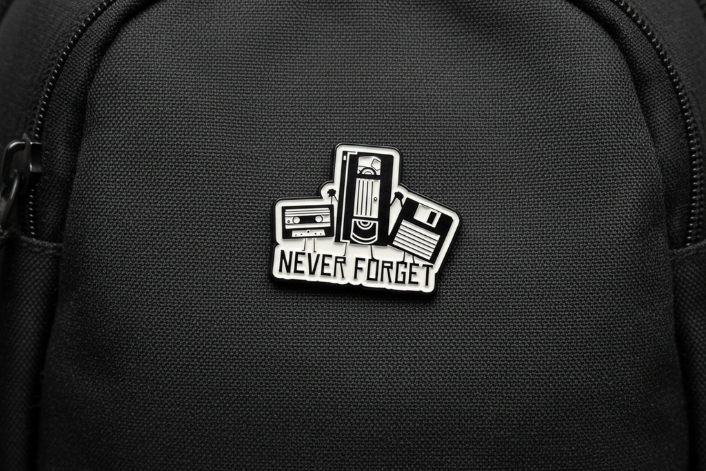 Pin with cassette tape design and 'Never Forget' text on a gray background