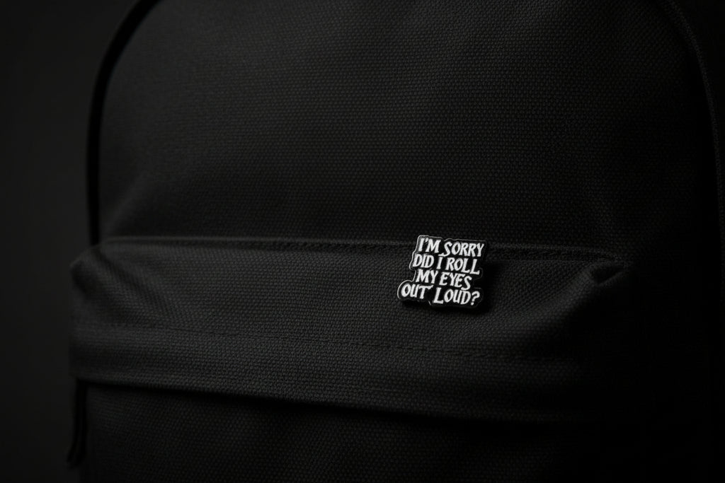 Black and white enamel pin with text on a gray background