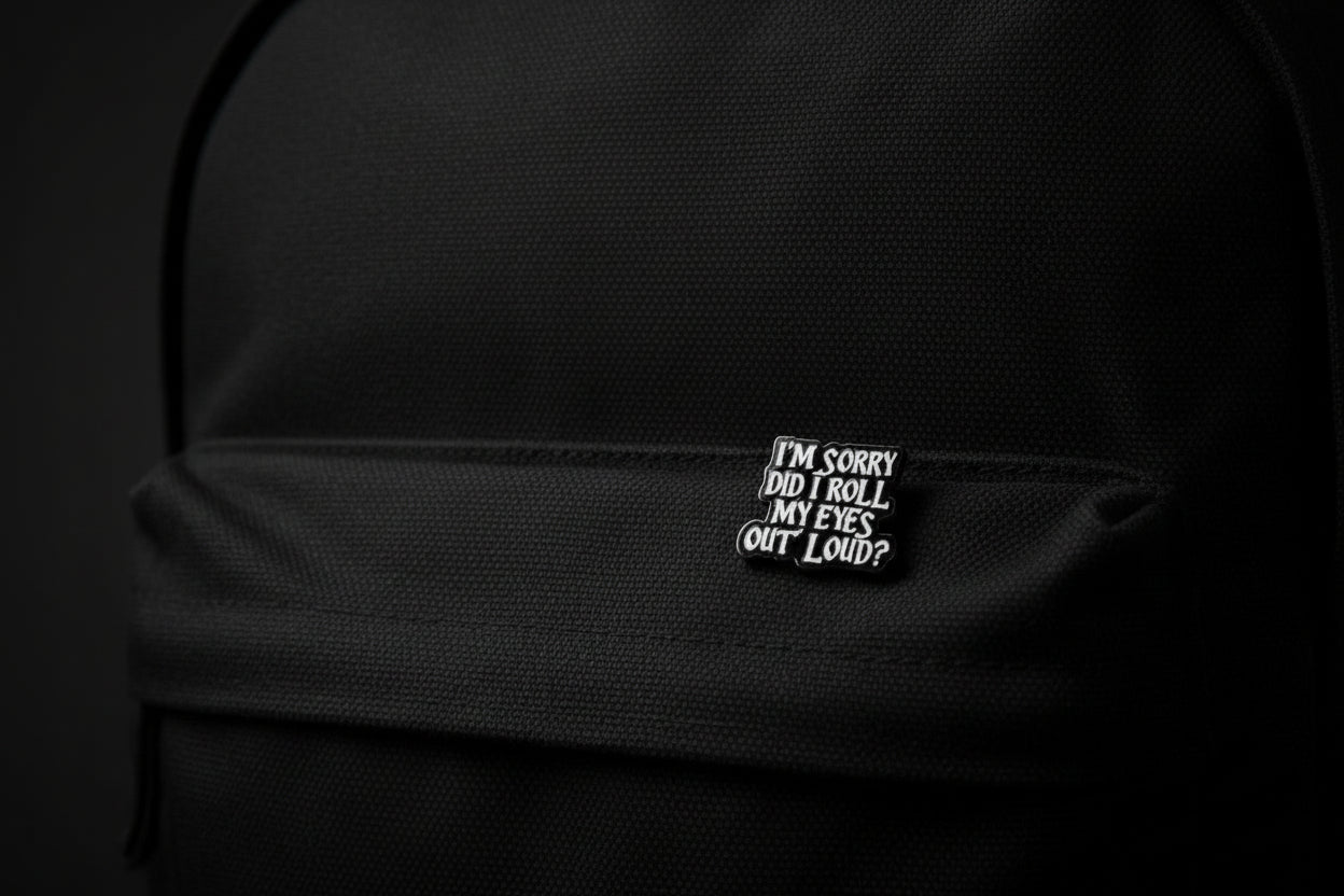 Black and white enamel pin with text on a gray background