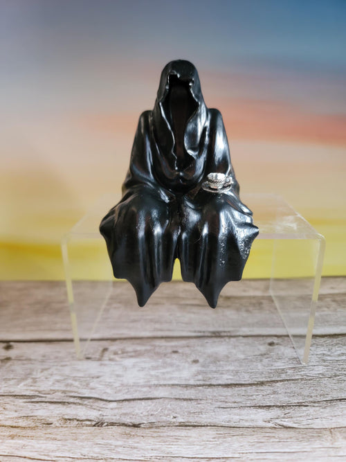 Black human shaped object on a clear stand with a white background