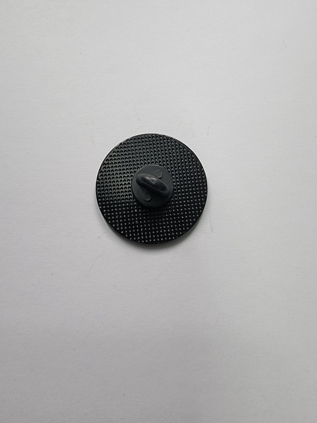 Black circular object with textured surface on a light gray background