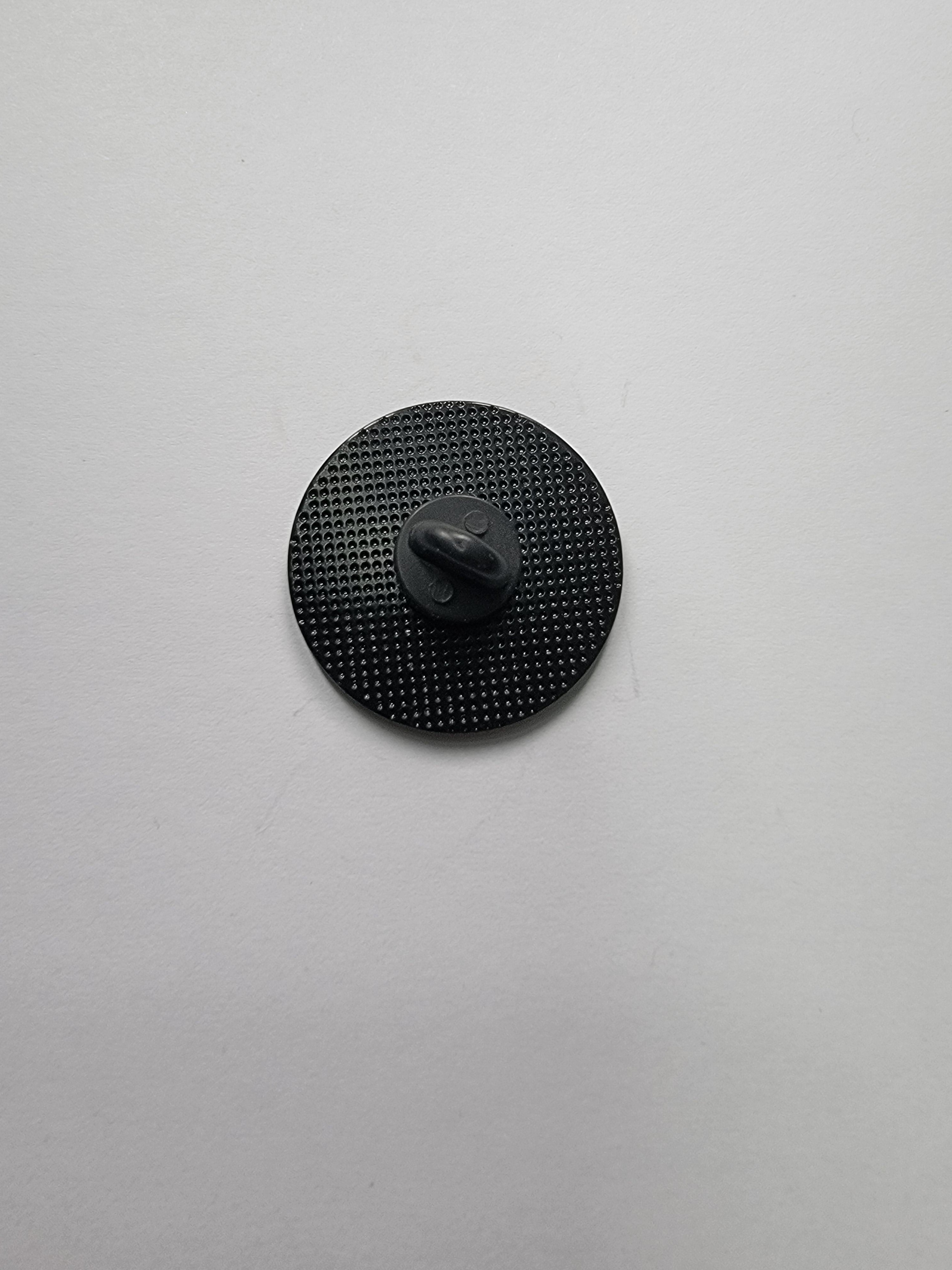 Black circular object with textured surface on a light gray background
