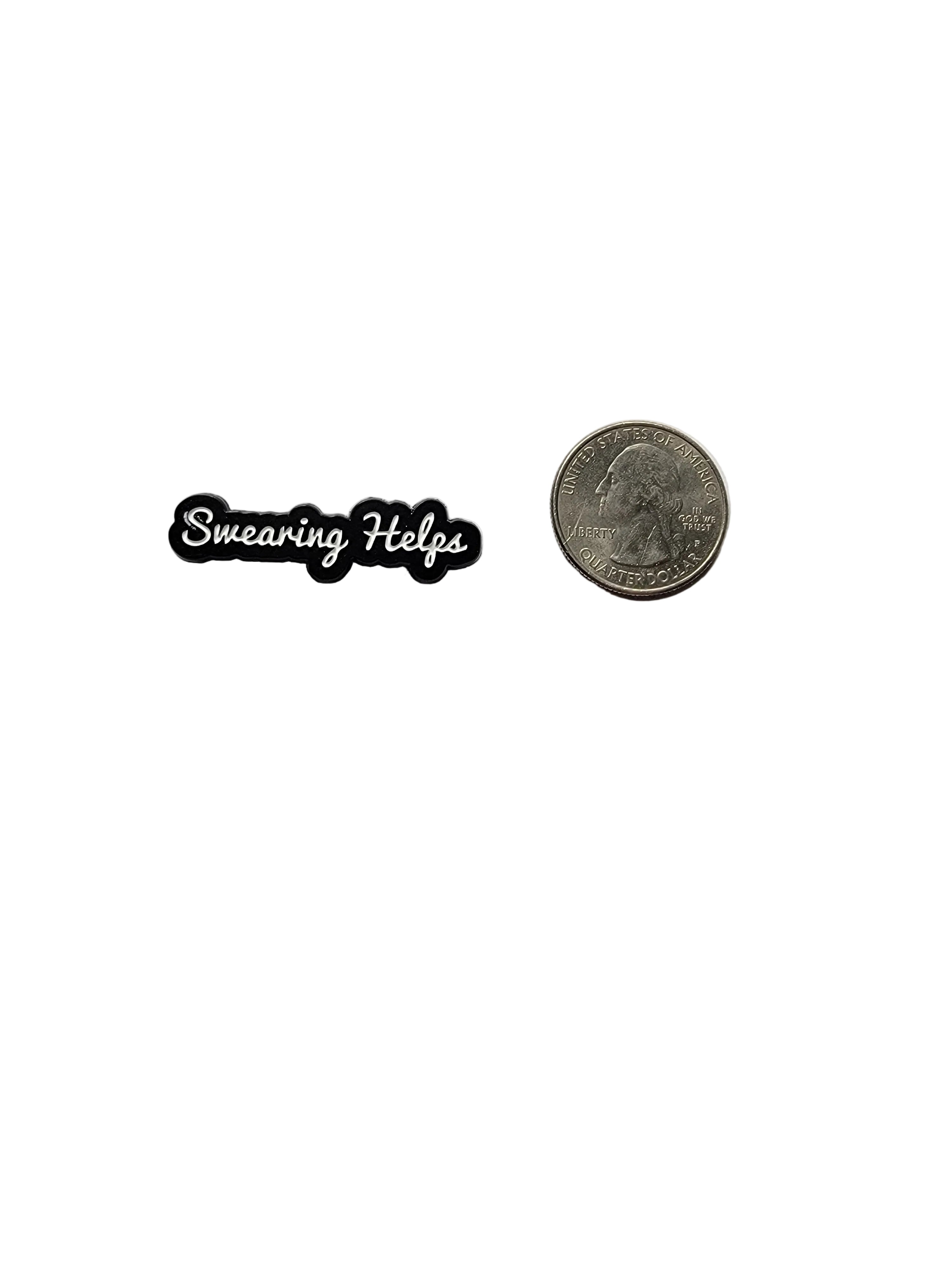 Small black and white pin with text that says "swearing helps" next to a quarter on a white background
