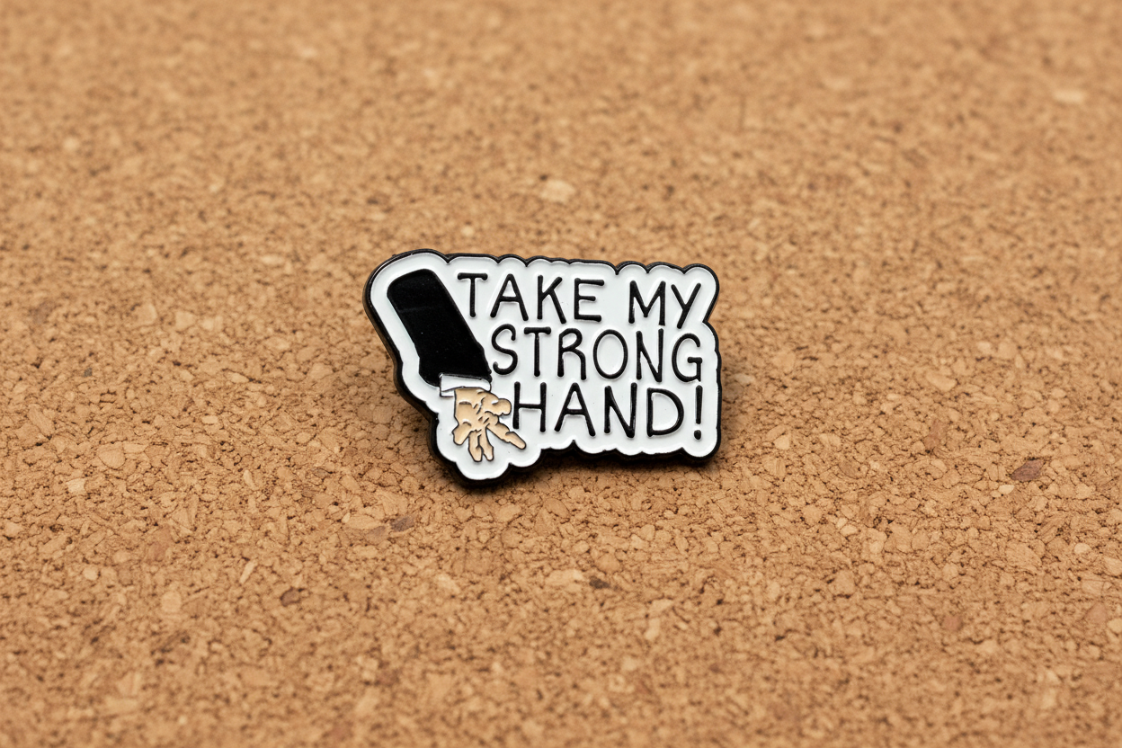 Pin with a design of a hand and text 'Take my strong hand' on a cork background