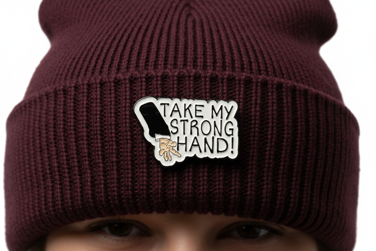 Pin with a design of a hand and text 'Take my strong hand' on a red beanie hat background