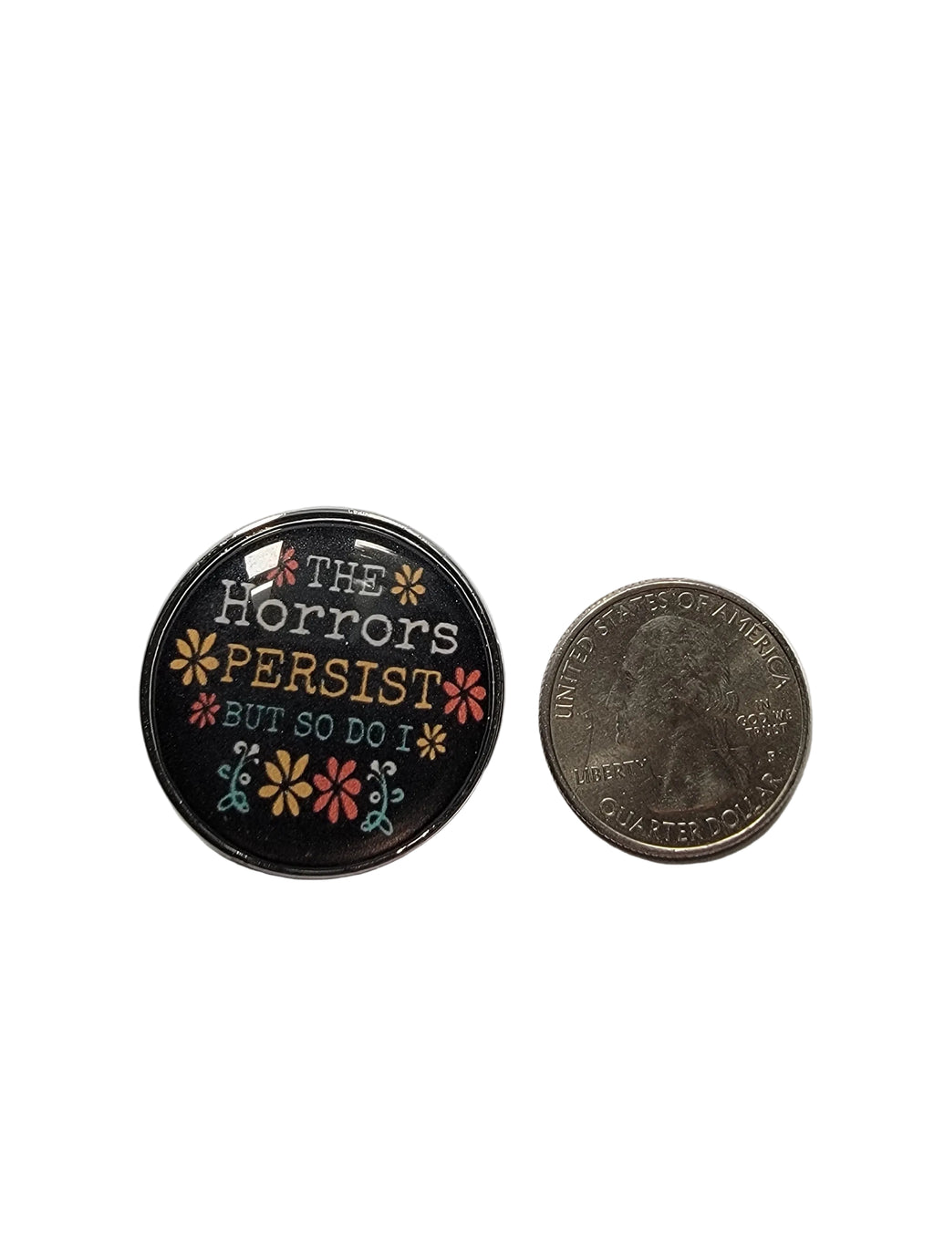 Small round badge with text and floral design next to a coin on a white  background