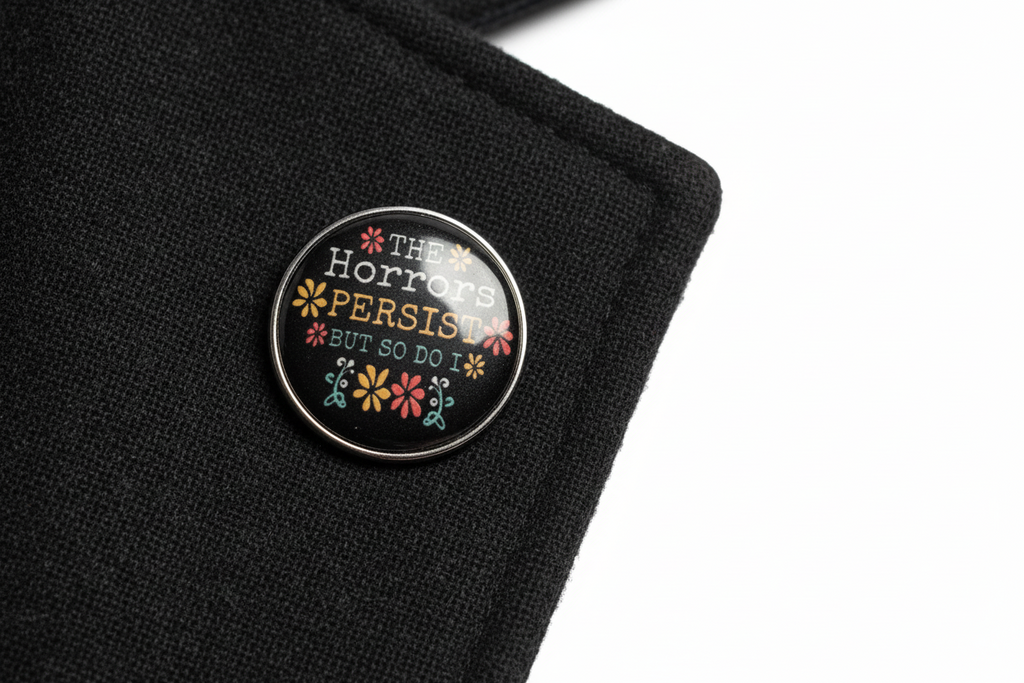 Round black pin with text and floral designs on a lapel background