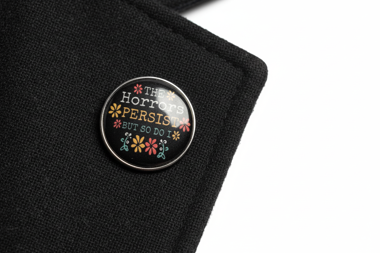 Round black pin with text and floral designs on a lapel background