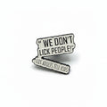 a white enamel pin with black text that says we don't lick people lies adults tell kids on a white background