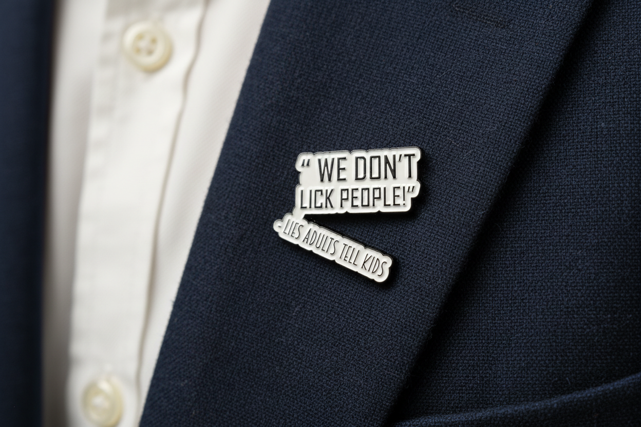 a white enamel pin with black text that says we don't lick people lies adults tell kids on a navy lapel background