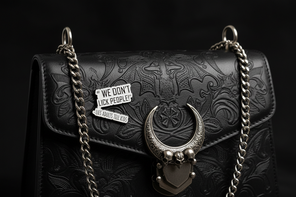 a white enamel pin with black text that says we don't lick people lies adults tell kids on a black purse background
