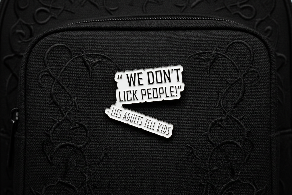 a white enamel pin with black text that says we don't lick people lies adults tell kids on a black bookbag background