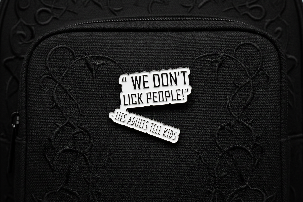 a white enamel pin with black text that says we don't lick people lies adults tell kids on a black bookbag background
