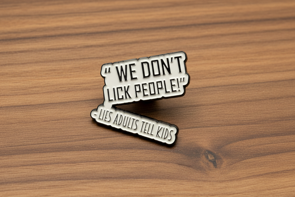 a white enamel pin with black text that says we don't lick people lies adults tell kids on a wood background