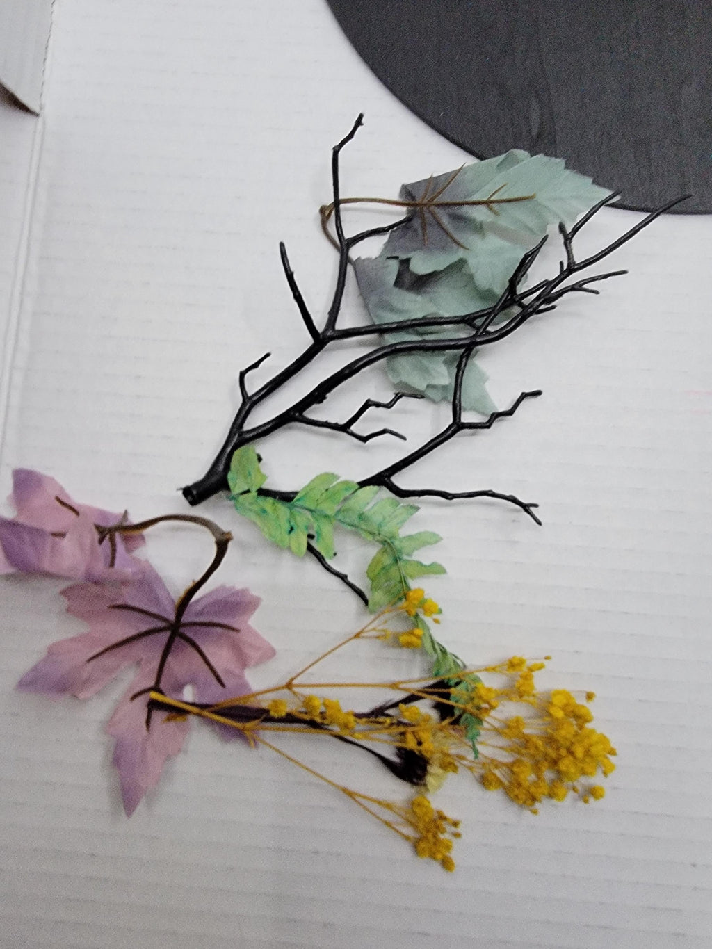 Artificial flowers and branches on a textured white surface