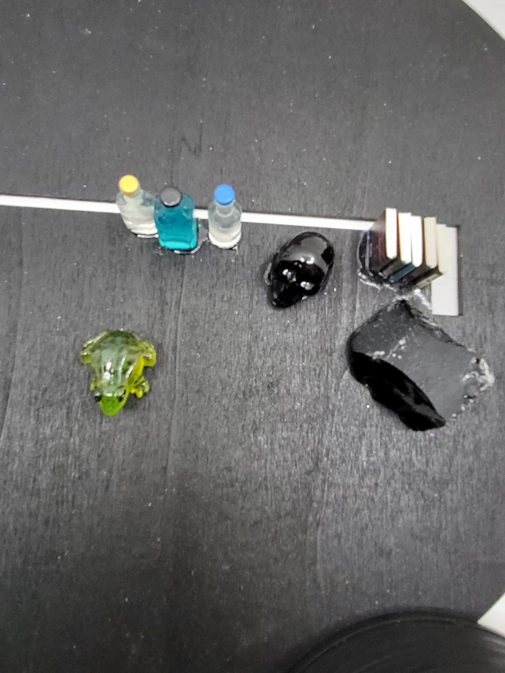 Small figurines on a dark surface with a white spot showing the gap for the witch hat top.