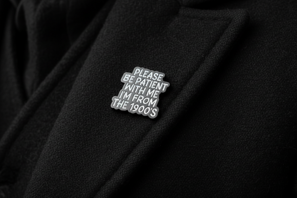 Black and white pin with text on a black fabric background