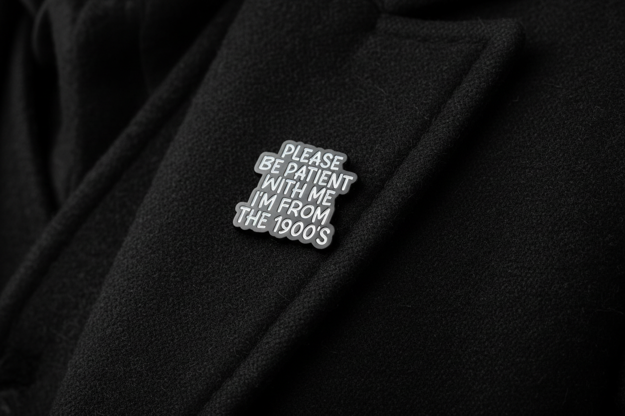 Black and white pin with text on a black fabric background