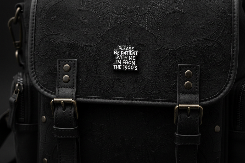 Black and white pin with text on a black fabric background