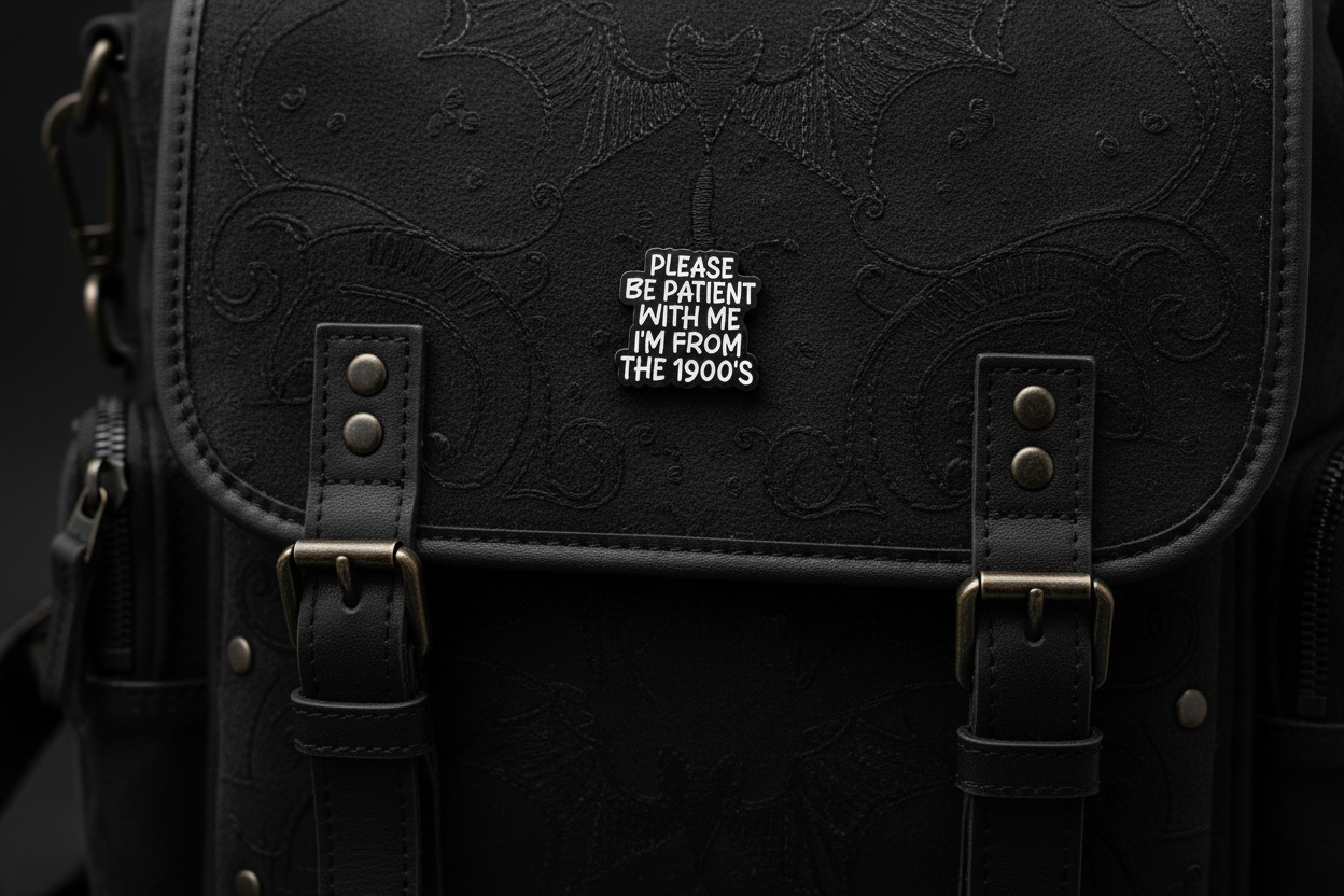 Black and white pin with text on a black fabric background