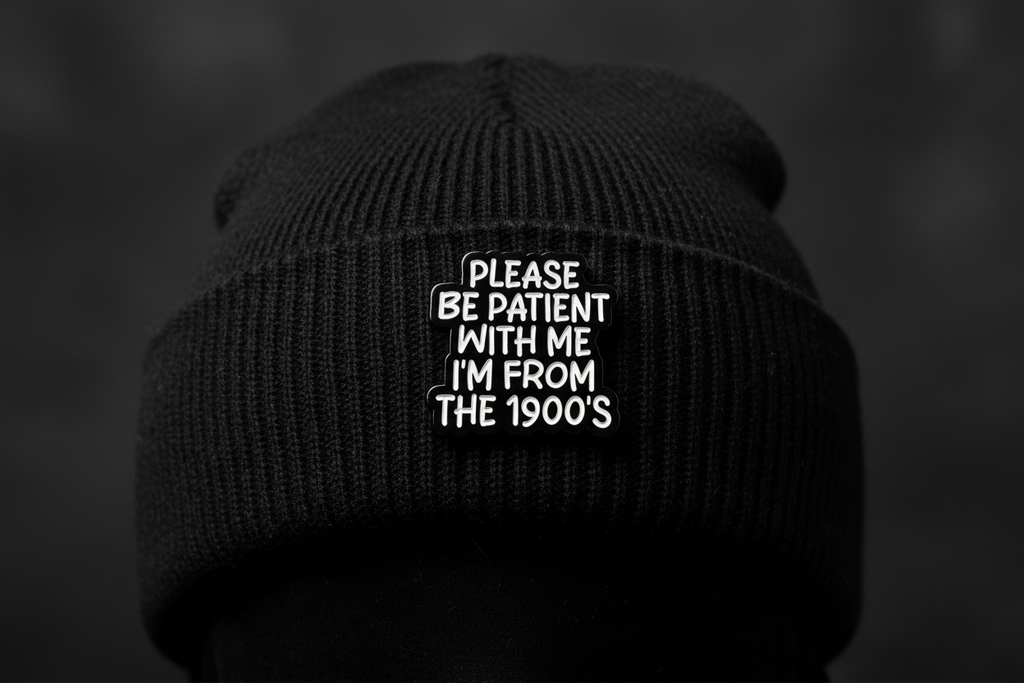 Black and white pin with text on a black beanie hat background