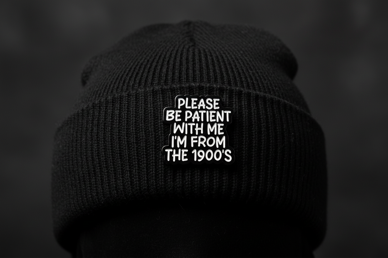 Black and white pin with text on a black beanie hat background