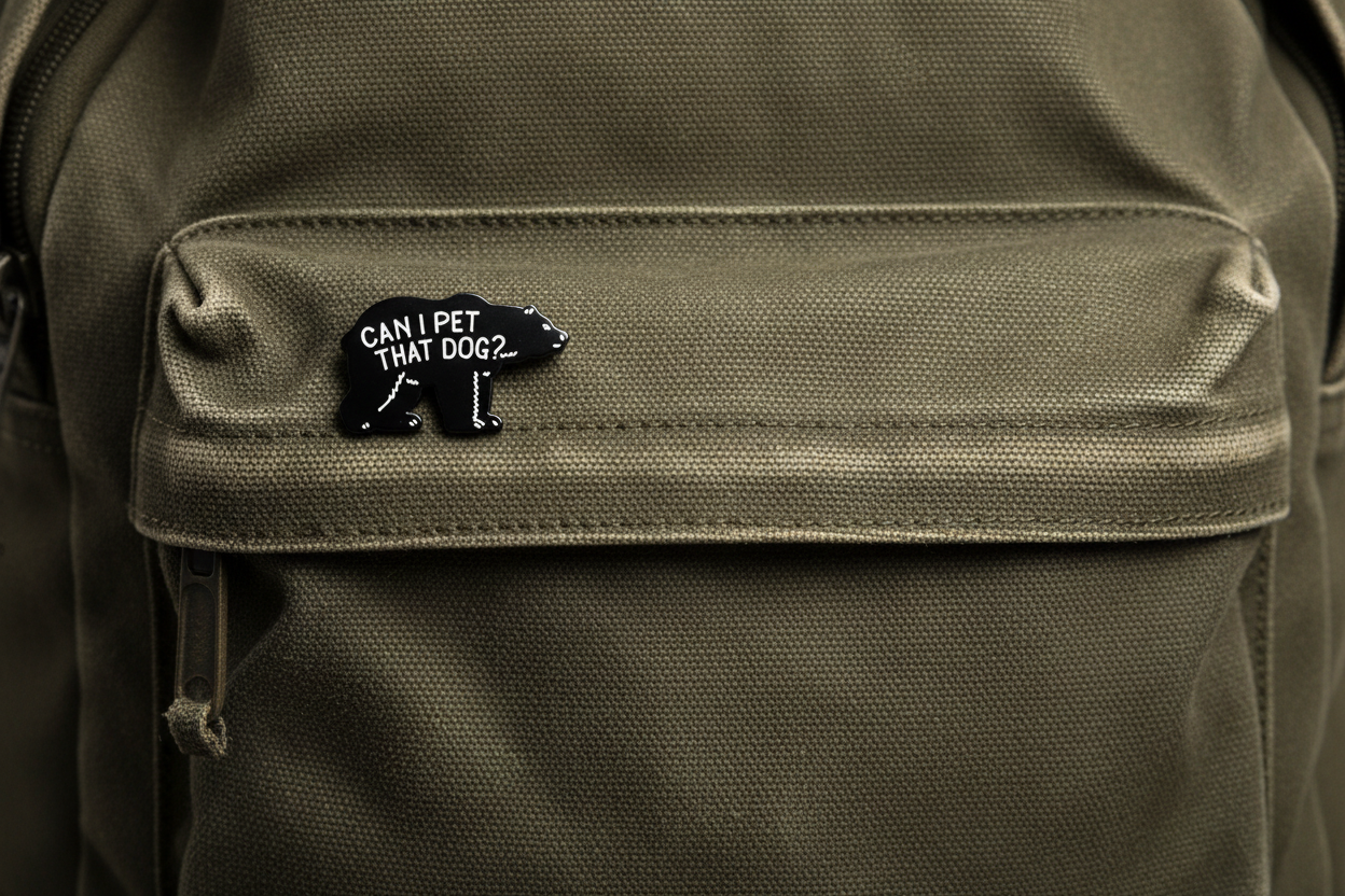 Black bear-shaped pin with text on a green fabric background