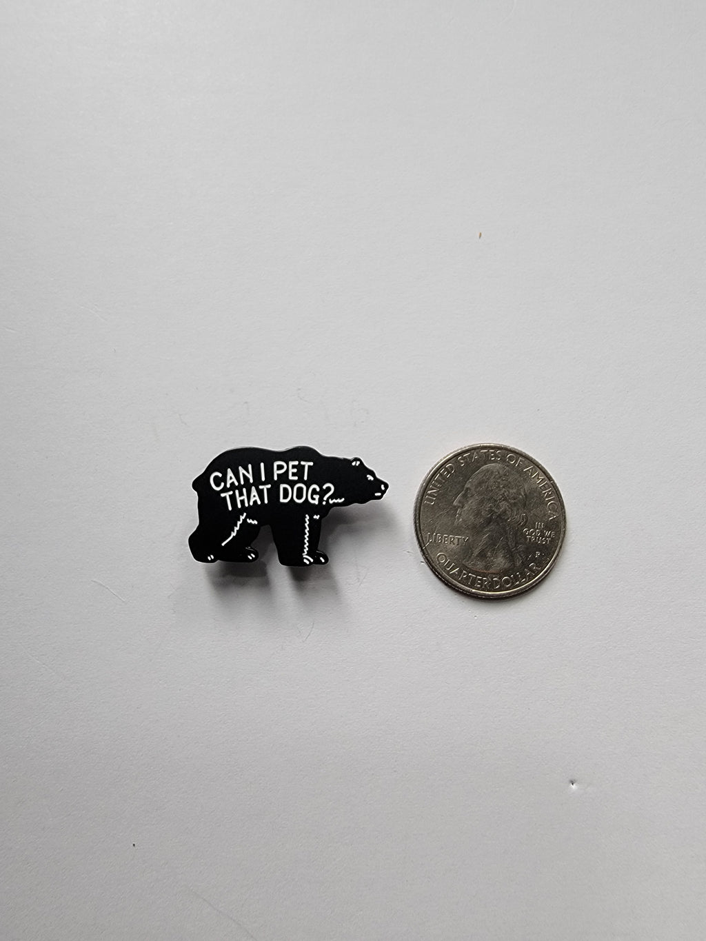 Small black object with text next to a quarter on a gray background