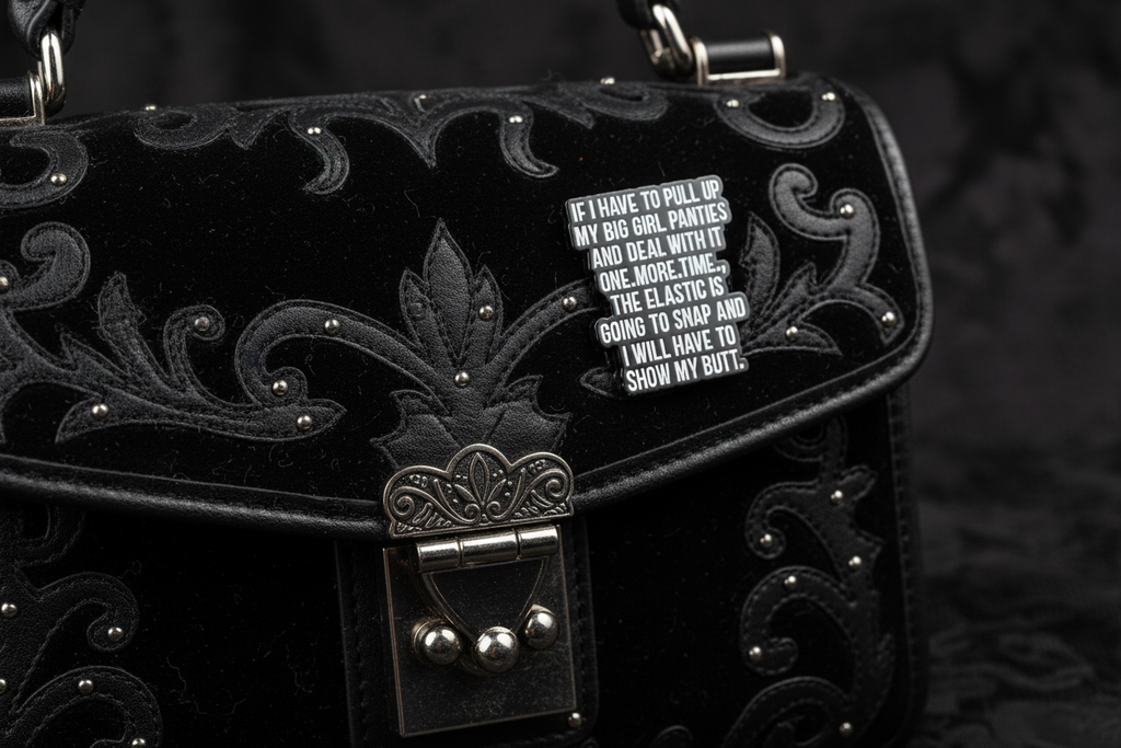 a black enamel pin with white text on a black purse background