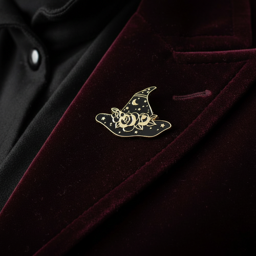 black and gold witch hat enamel pin worn on jacket lapel, goth pin styles for everyday wear