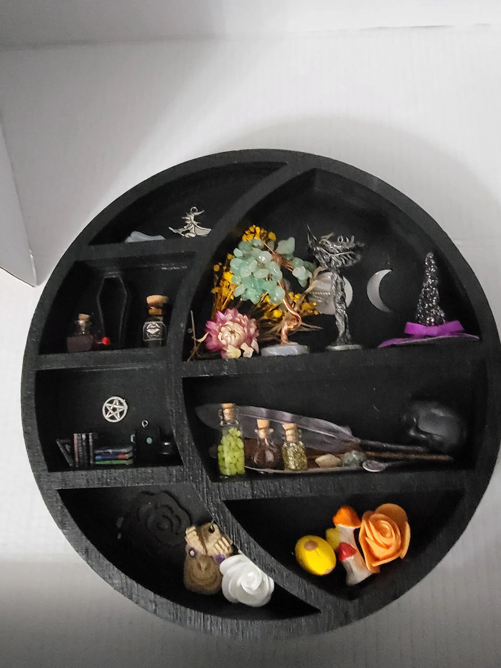 Circular black shelf with various decorative items on a white background