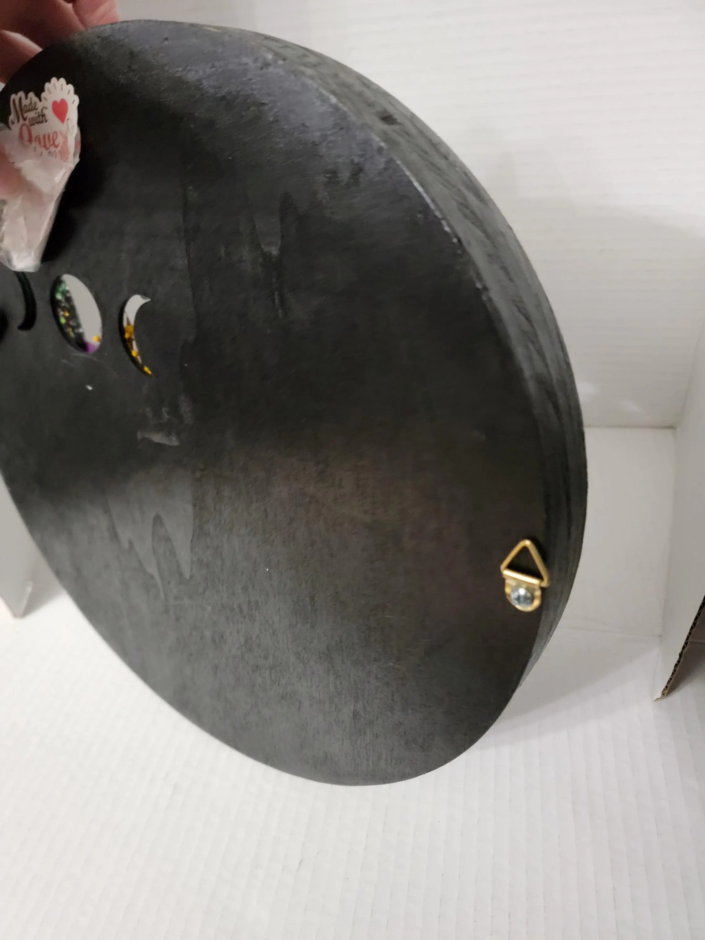 Black round object with gold accents on a white background