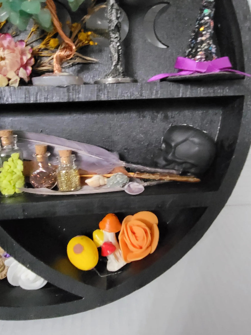 Decorative shelf with various small objects including a skull, flowers, and bottles.