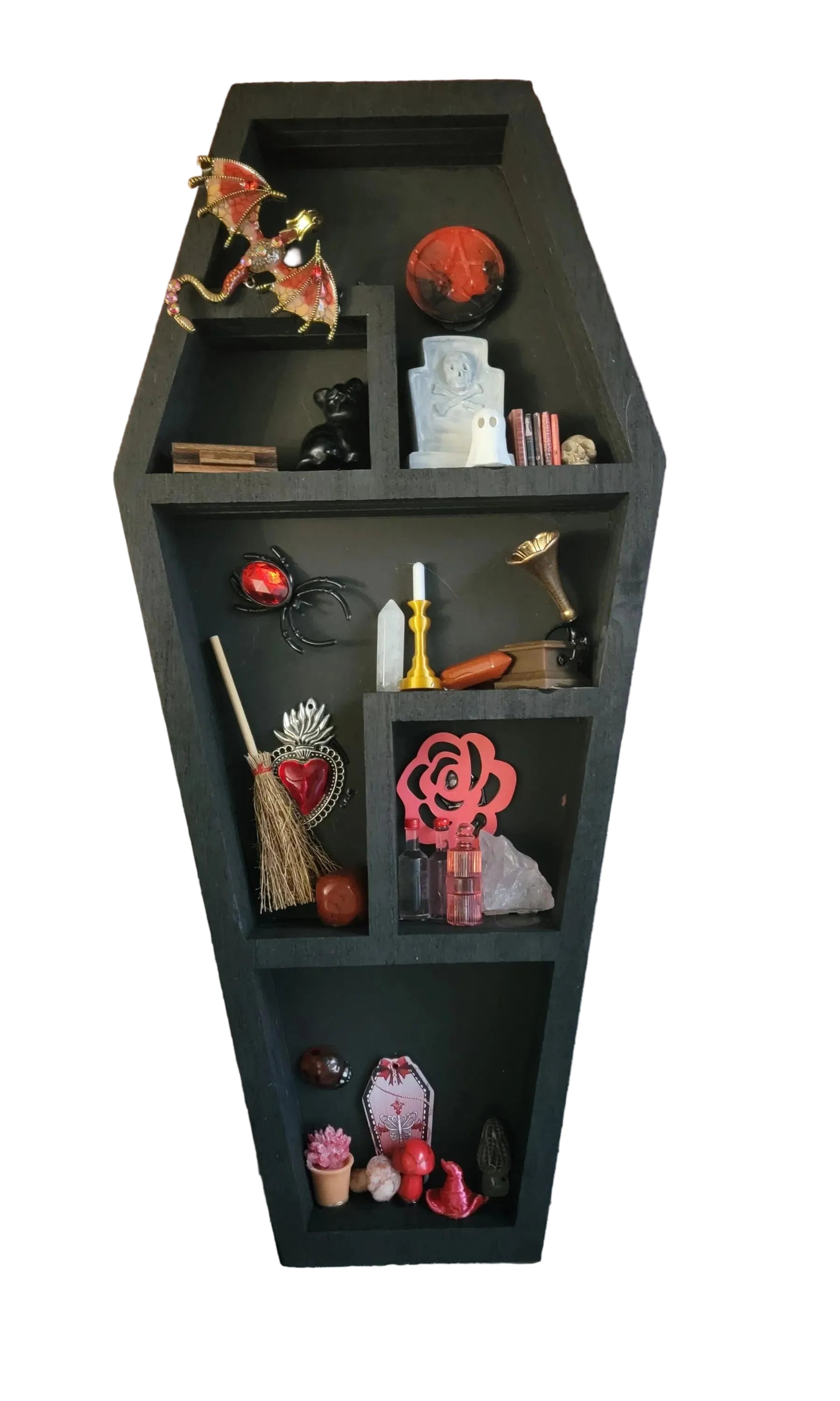 Black coffin-shaped shelf with decorative items against a white background.