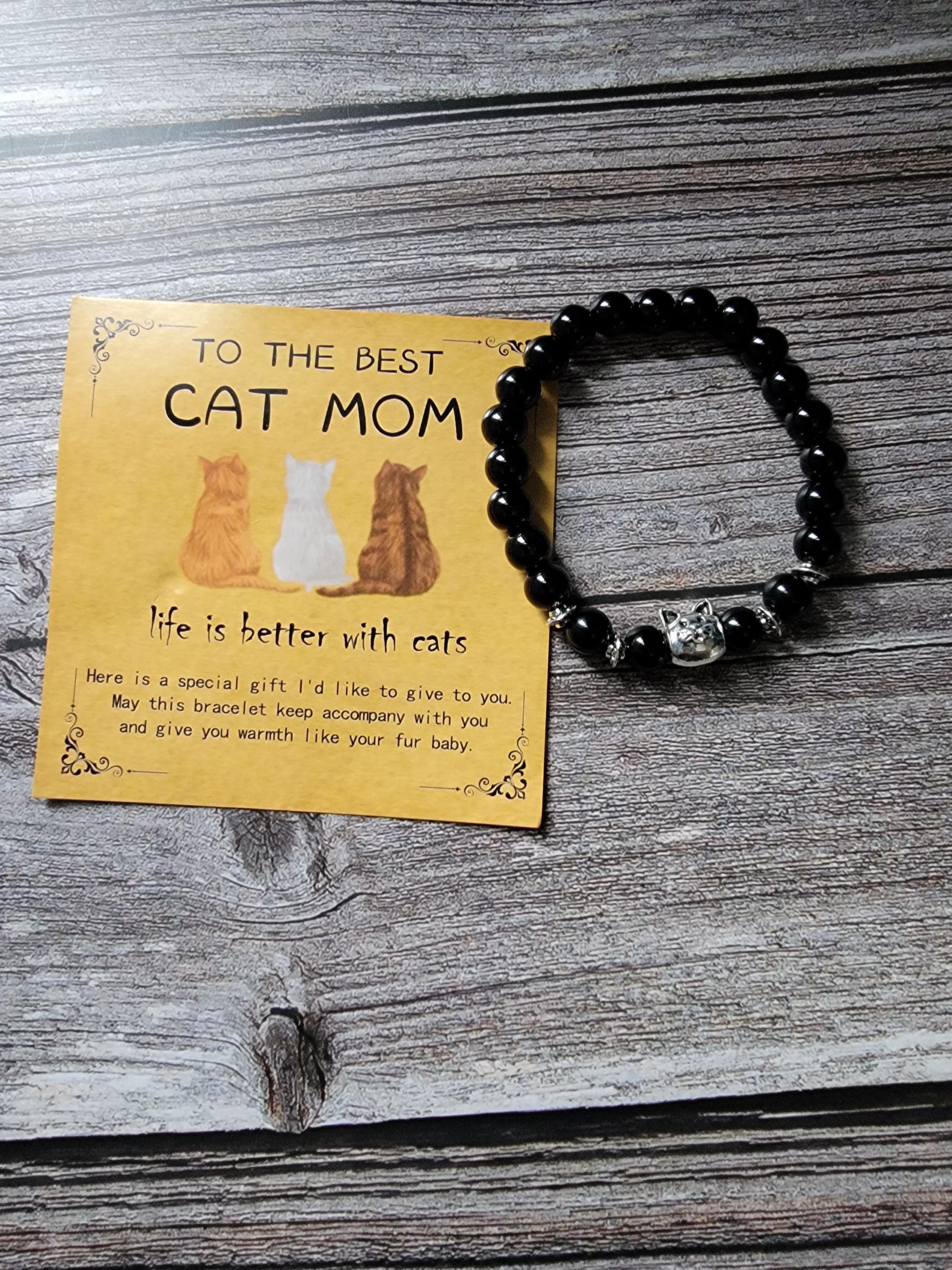 Black beaded bracelet on a wooden surface with a card reading 'To the best cat mom, life is better with cats'.