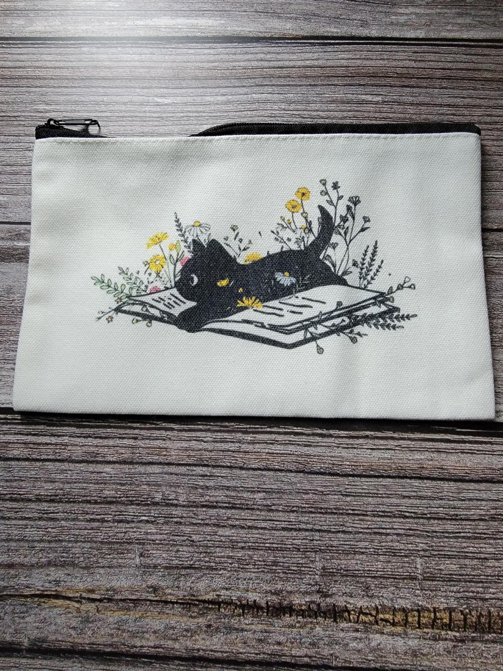 White pouch with black cat design on a wooden surface