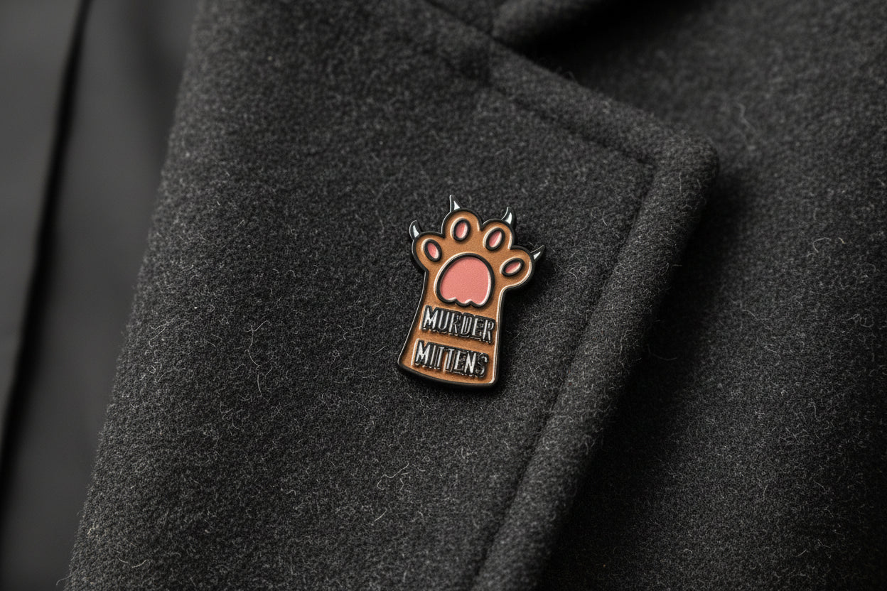 Small enamel pin with a paw design and text on a gray background